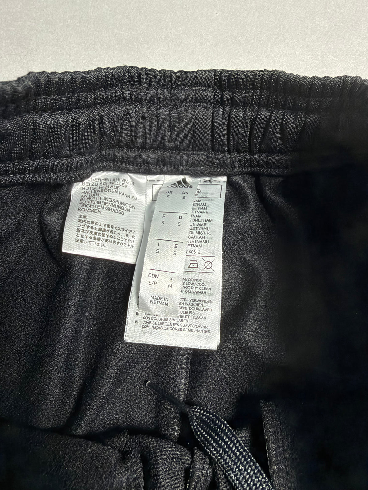 Dettaglio etichetta interna adidas con indicazione taglia S e istruzioni di lavaggio