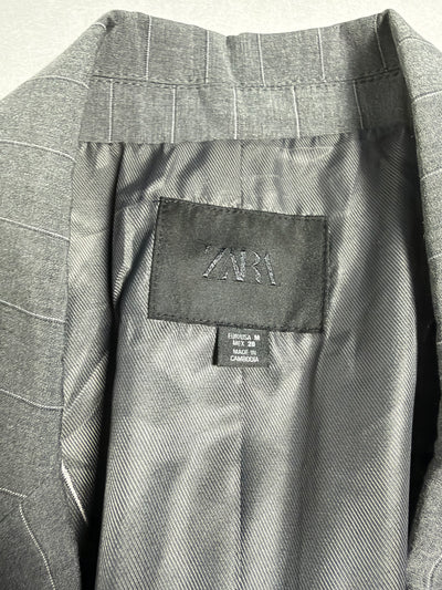 Primo piano dell'etichetta Zara con taglia M e fodera interna del blazer gessato