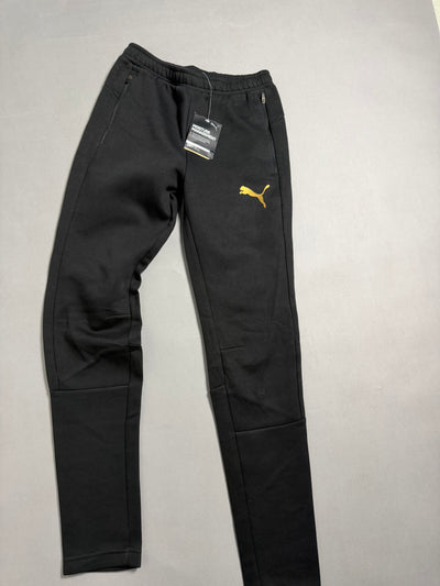Pantaloni sportivi neri PUMA Evostripe con logo oro stesi sul piano