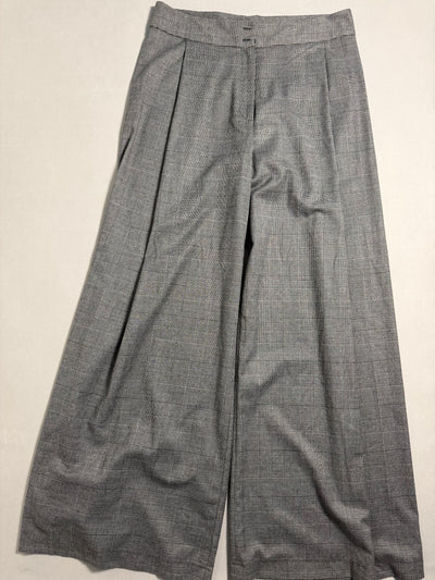 Pantaloni a gamba larga Zara Woman motivo principe di Galles grigio distesi su piano neutro