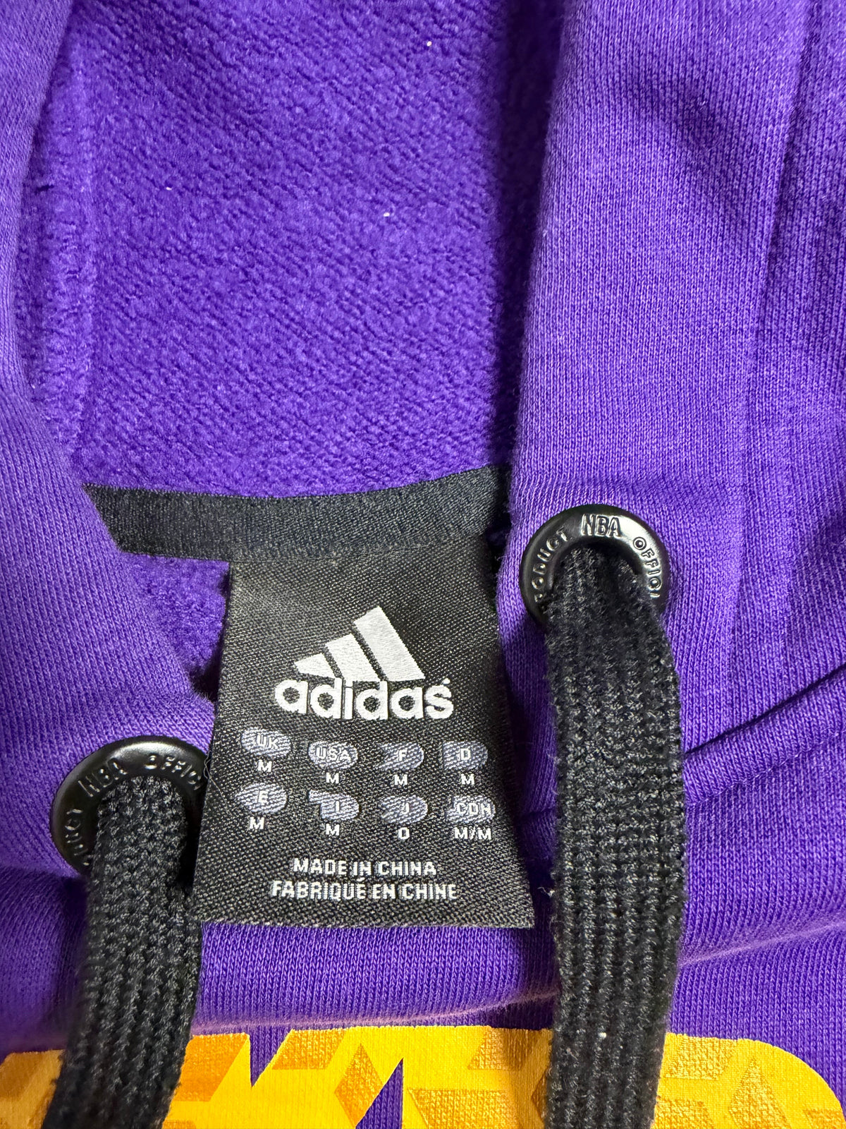 Dettaglio colletto con etichetta interna taglia M adidas e occhielli del cordoncino NBA