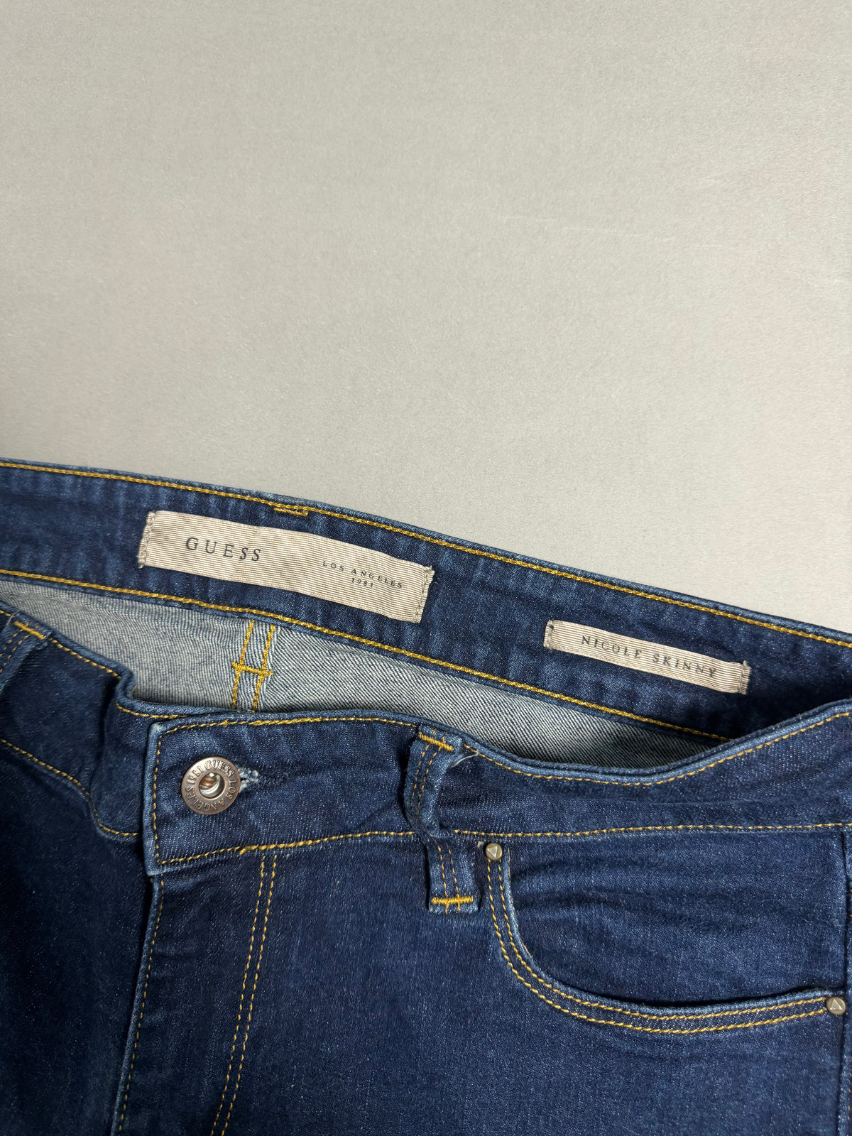 Dettaglio della cintura interna con etichette GUESS e modello Nicole Skinny