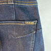Dettaglio del logo metallico Guess sulla tasca posteriore dei jeans