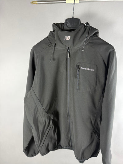 Vista frontale di giacca New Balance nera con cappuccio, zip e taschino sul petto