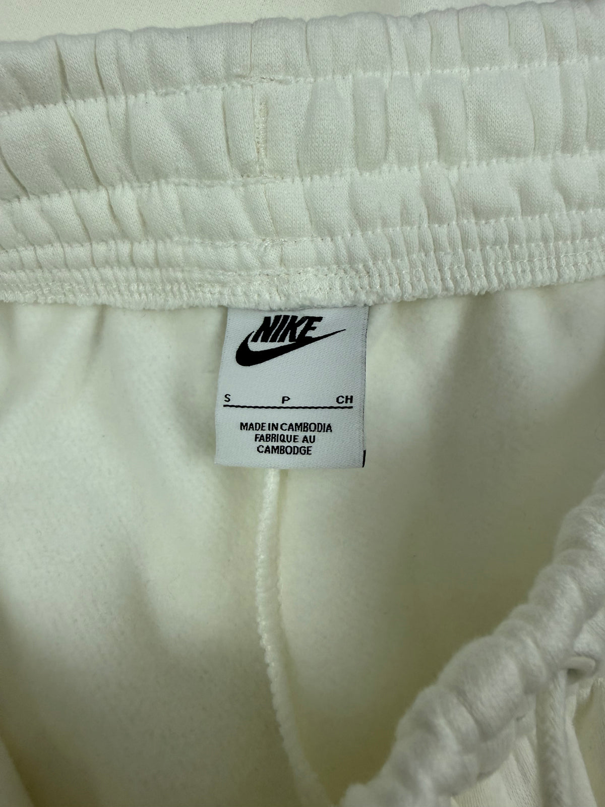 Etichetta interna Nike con taglia S su pantaloni tuta panna