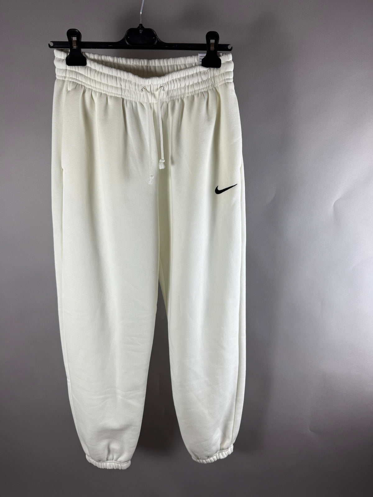 Vista frontale di pantaloni tuta Nike panna con logo Swoosh nero