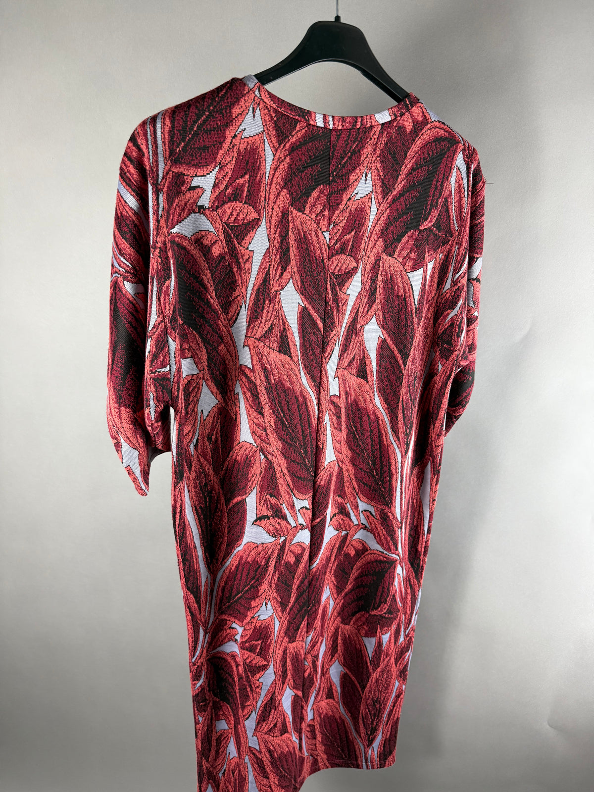 Vista posteriore del vestito Zara rosso fantasia foglie appeso su gruccia