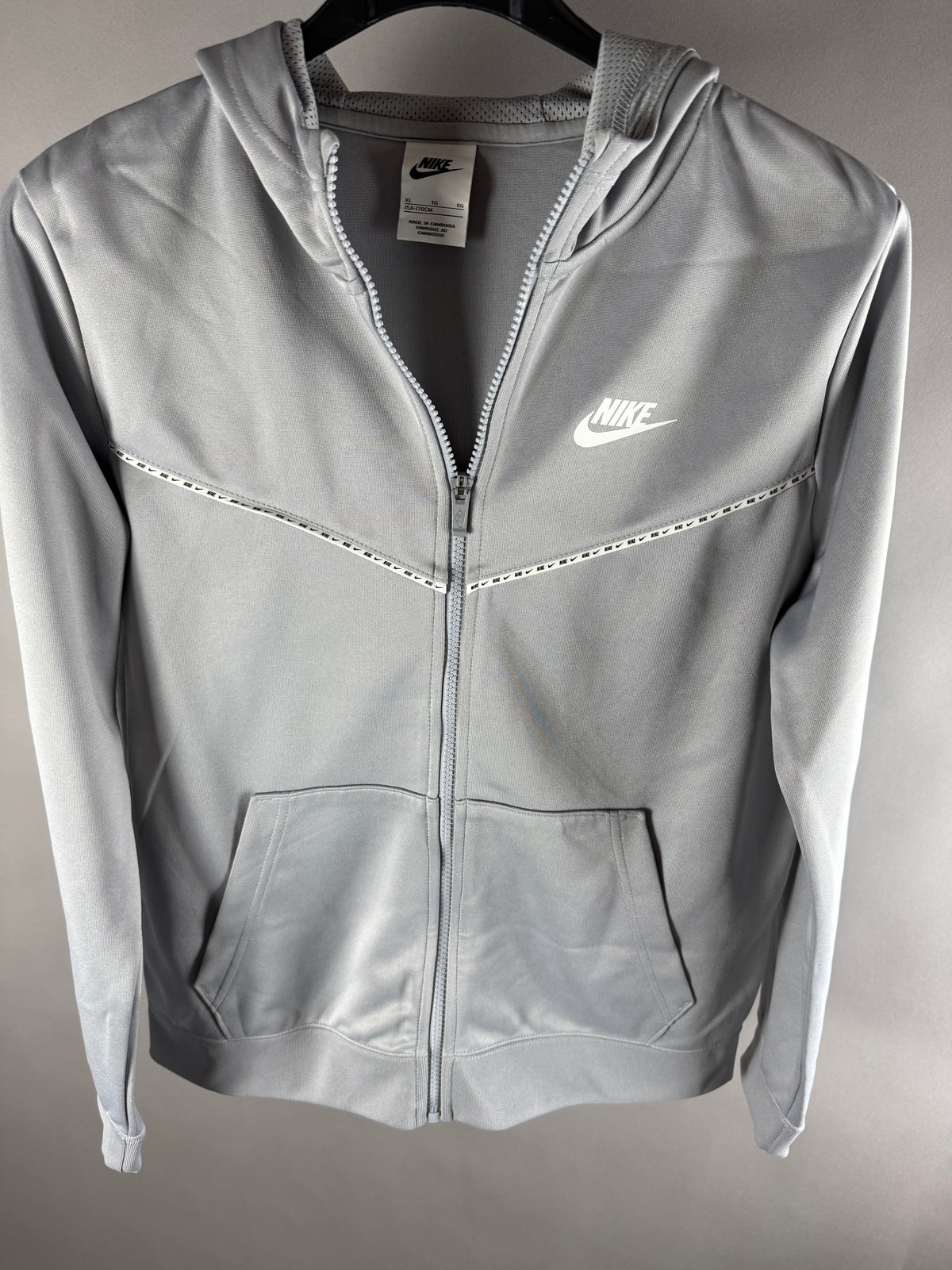 Vista frontale di felpa Nike grigia con cappuccio, zip e logo bianco