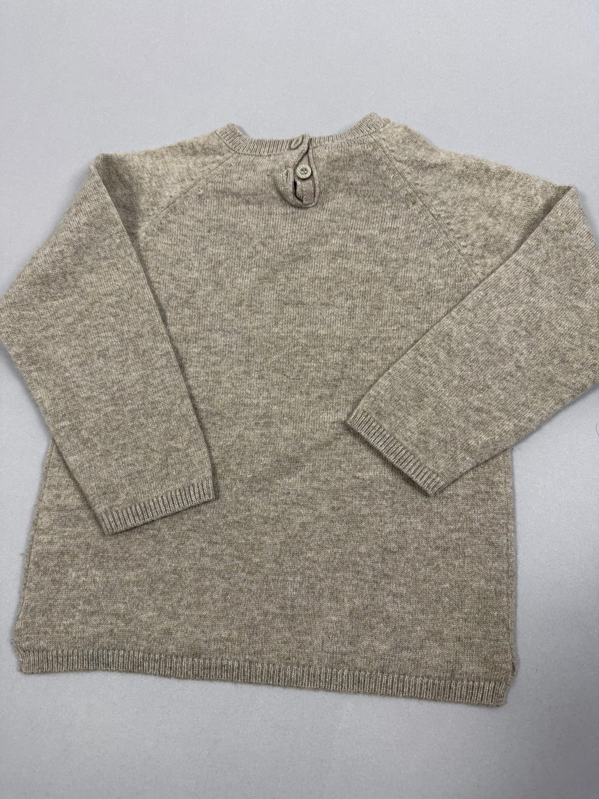 Vista posteriore del pullover beige con apertura a bottoni sul collo