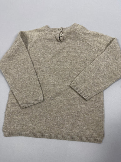 Vista posteriore del pullover beige con apertura a bottoni sul collo