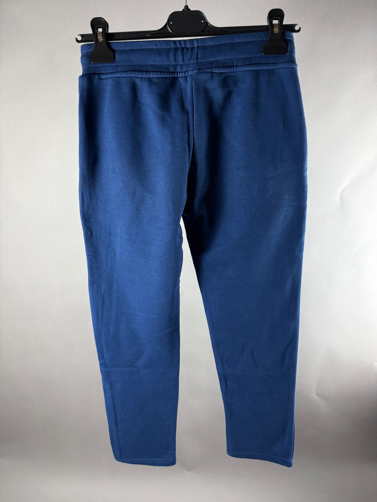 Vista posteriore dei pantaloni jogger blu navy con piccolo segno sulla gamba sinistra
