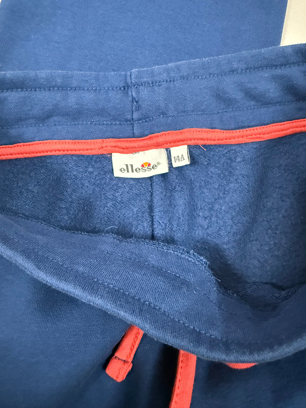 Etichetta interna Ellesse con taglia 14A sui pantaloni blu