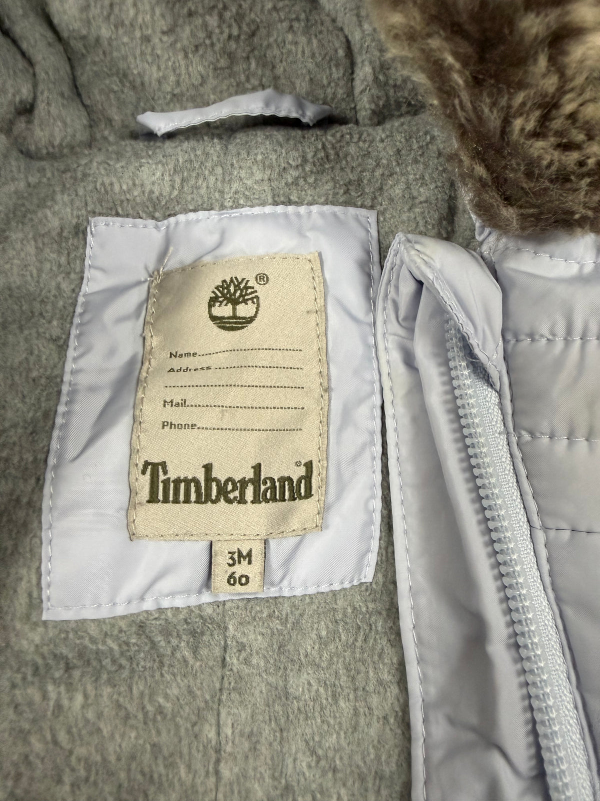 Etichetta Timberland interna con taglia 3M 60 sulla tuta da neonato